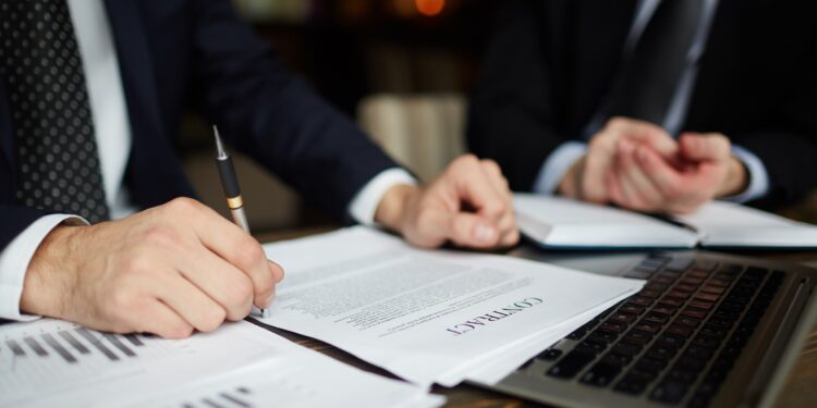 Here are a few benefits of Whitepapers for a B2B firm 1 Closeup portrait of unrecognizable successful businessman wearing black formal suit reviewing documents and signing contract during meeting